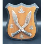 A Vintage Gurkha Regiment Wooden Shield, fitted with cross Kukri's and 4 cap badges.