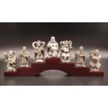 7 Pewter Chinese Figurines on a wooden pedestal. A well-detailed selection of seven different