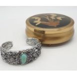 A white metal (untested) and turquoise bangle. Presented in a vintage brass round case with dried