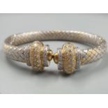 AN OVAL 18CT YELLOW AND WHITE GOLD BANGLE WITH DIAMOND ENCRUSTING. 31.5gms.