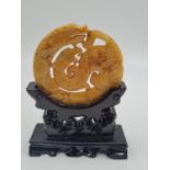 A Chinese, carved, yellow-orange, jade disc (amulet?) with two protecting mythical beasts. Presented