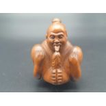 An intricately carved boxwood, Japanese, netsuke of a contortionist man indulging in self-