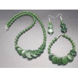 A modern spinach green jade necklace, bracelet and earrings set in a presentation box. Necklace