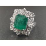AN 18CT WHITE GOLD RING SET WITH A LARGE EMERALD CUT NATURAL EMERERALD CENTRE STONE AND 16 ROSE