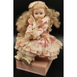 A Vintage Doll Dressed in Pink Lace sits atop a Musical Box. Moves arm as Memories, by Andrew