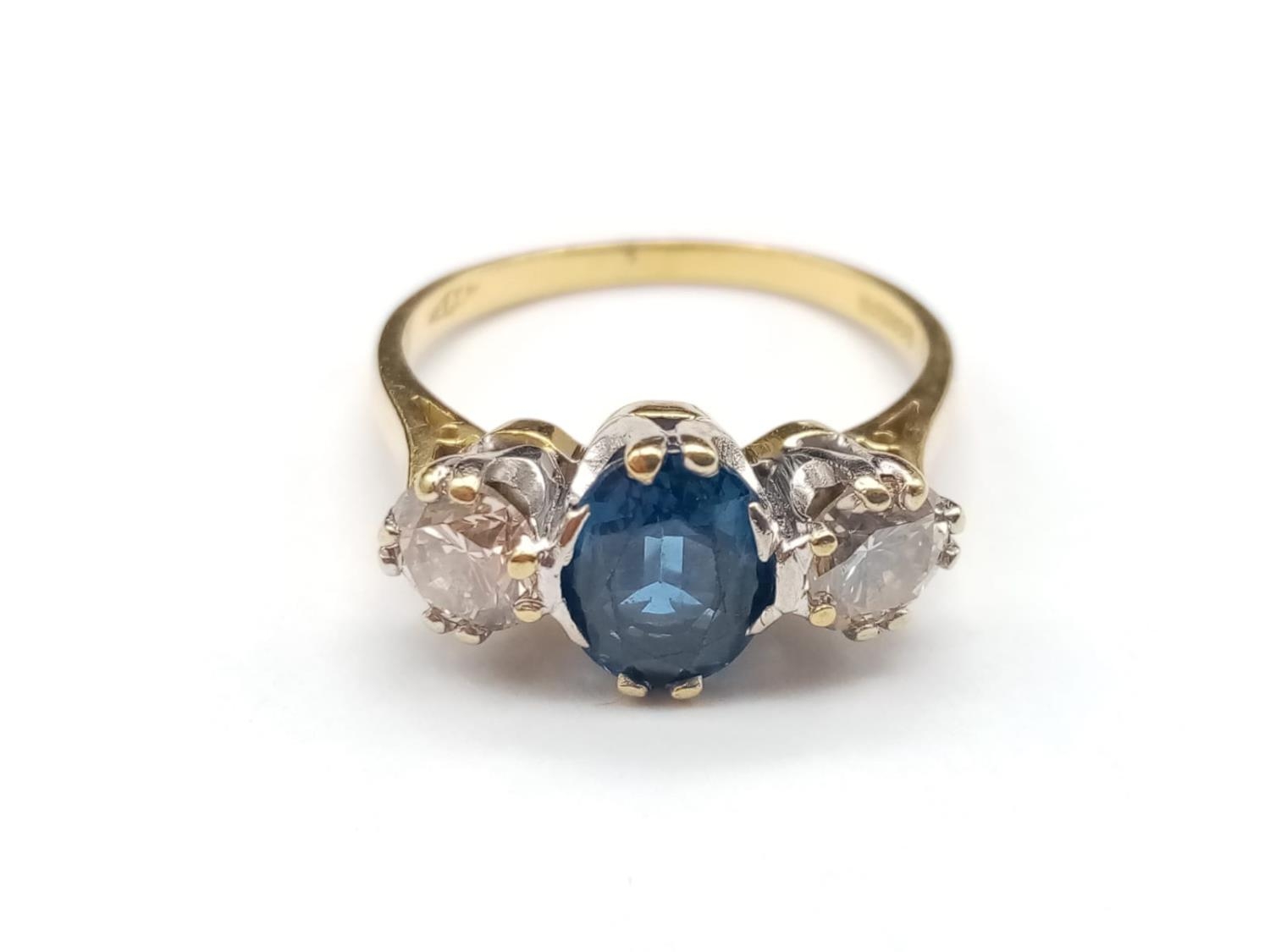 AN 18K YELLOW GOLD RING WITH LARGE OVAL SAPPHIRE CENTRE STONE FLANKED BY TWO BRILLIANT DIAMONDS. 4.