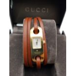 Designer Gucci Ladies Watch. Thin Brown Leather Wraparound Strap. Gold tone case. Silver Dial.