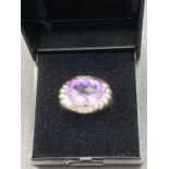 Stone set Silver ring having large oval AMETHYST to top with Corinthian design shoulders and clear