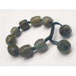 A GREEN ONYX BRACELET MADE UO OF 10 SHAPED ONYX STONES ON A PLAITED GREEN ROPE. 88gms 18cms