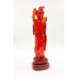 A Chinese, engraved amber resin statue of an emperor's concubine, carrying a flower. Total height: