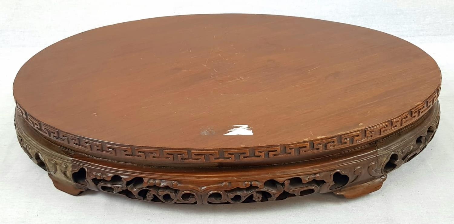 AN EARLY CHINESE OVAL SHAPED WOODEN STAND WITH TRADITIONAL DECORATION. 50 X 32cms 3.6kg