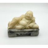 A VINTAGE WHITE JADE BUDDHIST FIGURE RECLINING ON MARBLE BASE. 1.83kgs 15 x 12cms