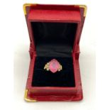 A 9K GOLD DRESS RING WITH LARGE PINK CENTRE STONE FLANKED BY WHITE STONES. 3.9gms size O