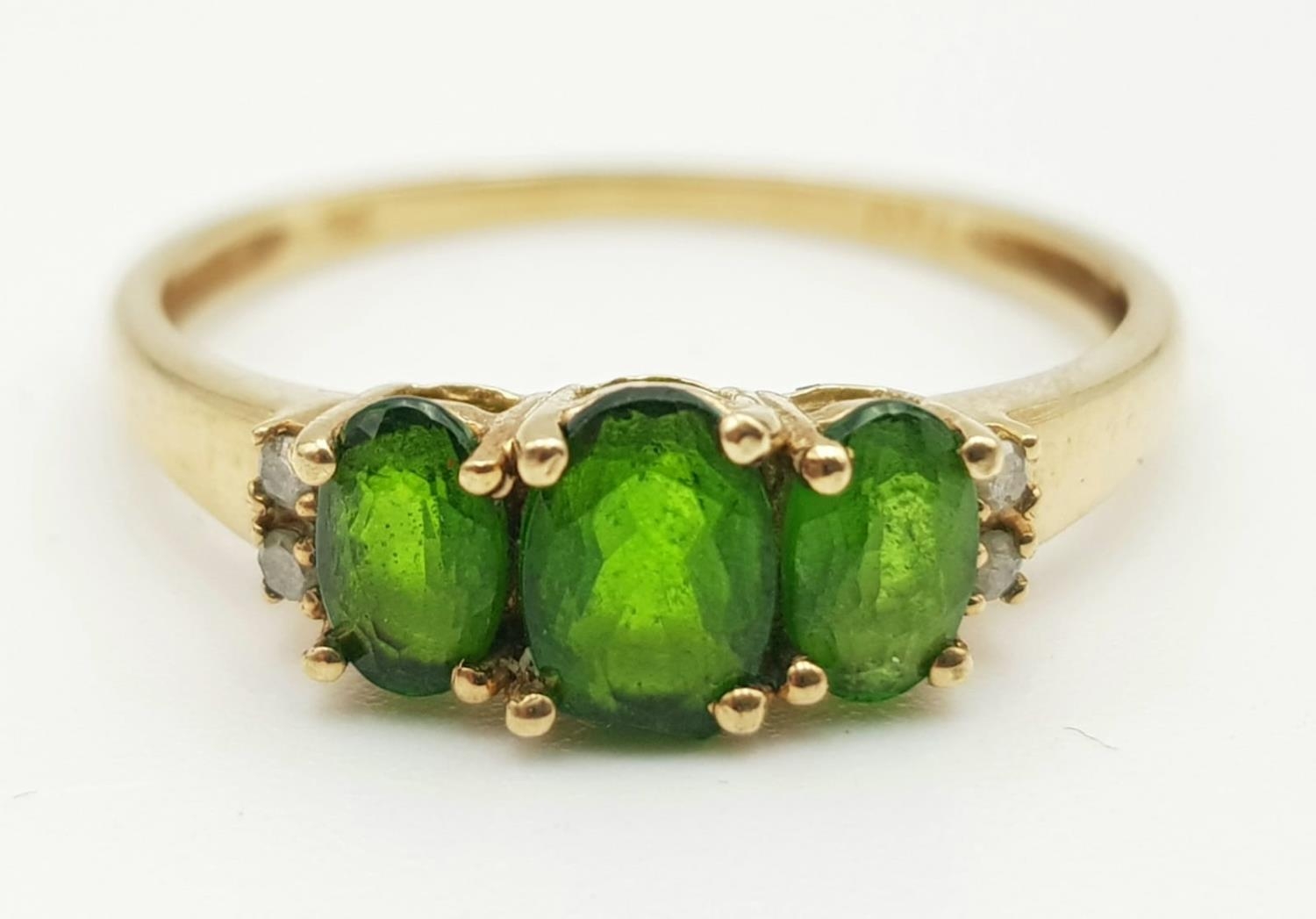 A 9K GOLD RING WITH GREEN TITANITE TRILOGY FLANKED BY 2 SMALL DIAMONDS ON EACH SIDE. 1.45gms size P