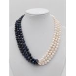 A glamourous, three rows of black and white pearls necklace with a flower shaped, hand carved,