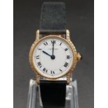 18k gold Cartier ladies wristwatch with white round face and diamond bezel, black leather strap.