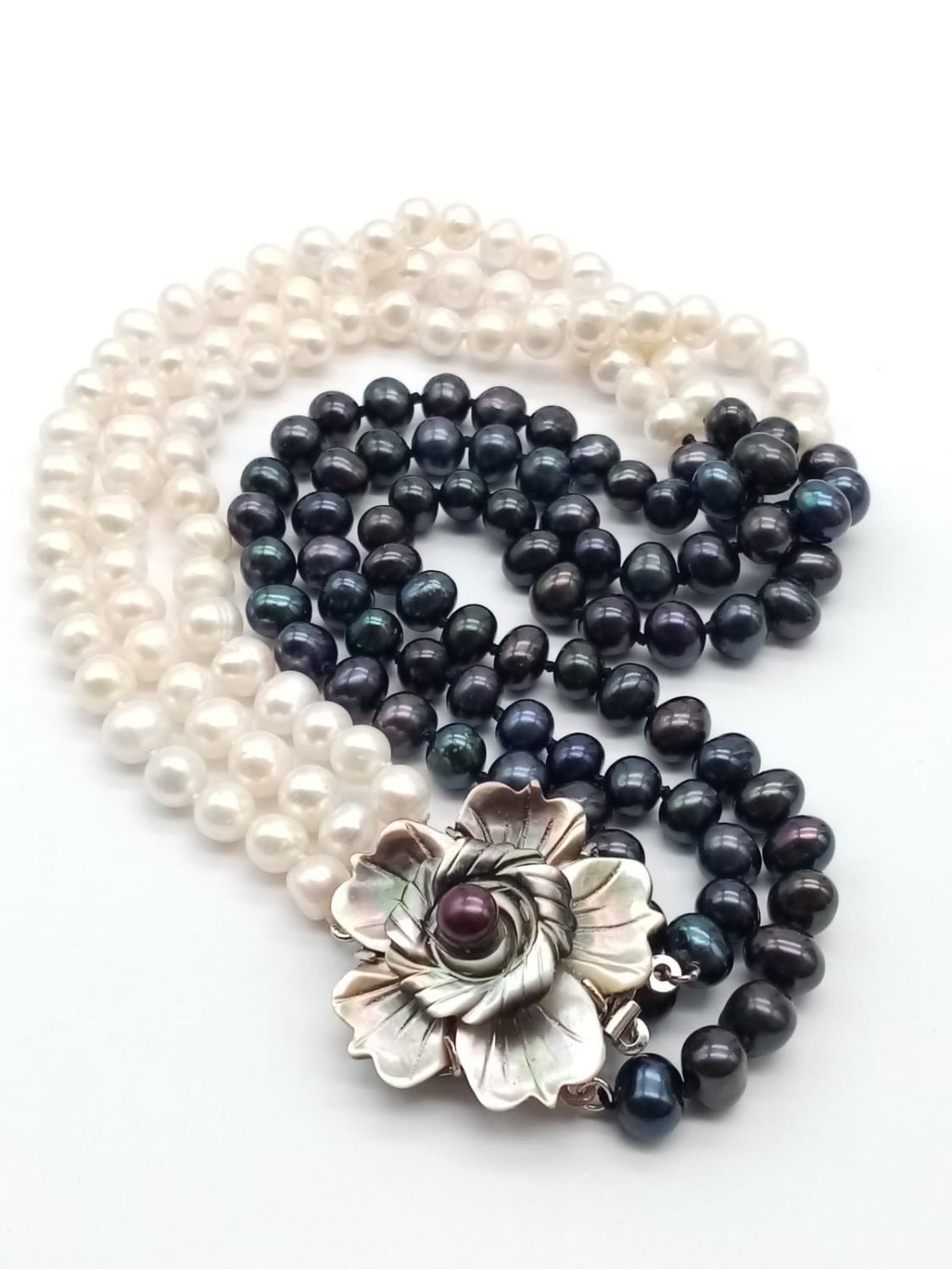 A glamourous, three rows of black and white pearls necklace with a flower shaped, hand carved, - Image 3 of 5