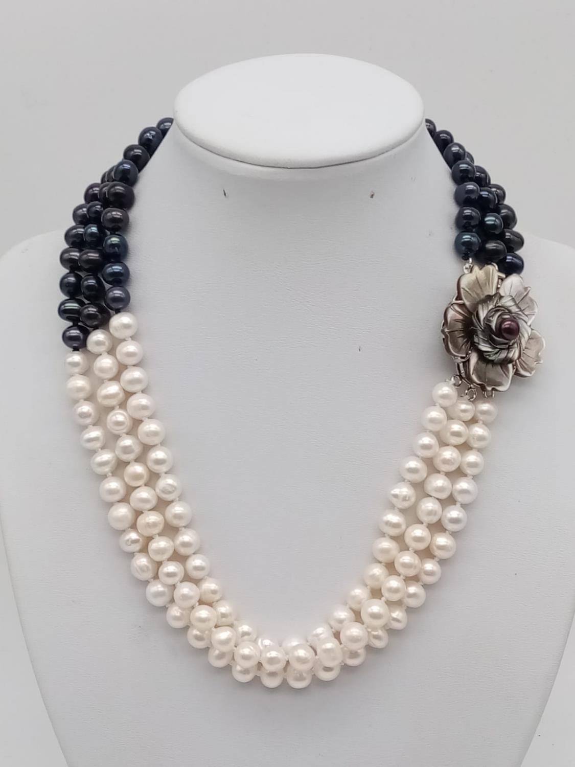 A glamourous, three rows of black and white pearls necklace with a flower shaped, hand carved, - Image 2 of 5
