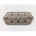 A refined Art Deco diamond and blue sapphires brooch. Weight 9.7g. Dimensions: 5.2x2.2x0.5 cm.