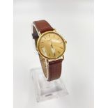 An 18K Yellow Gold Cased Baume and Mercier Ladies Watch. Brown leather strap, gold dial. Quartz