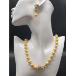 A rare and beautiful Cartier style yellow pearl necklace and earrings set in a presentation box.