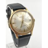 A Vintage Garrard Automatic Gold watch. Black leather strap. 9K yellow gold case. Silver dial. In