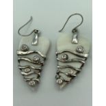 Pair of mother of pearl and silver earrings having modernistic silver work with clear Zirconias.