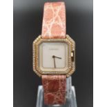 A LADIES 10K GOLD CARTIER DRESS WATCH WITH DIAMOND BEZEL , SILVER FACE AND MANUAL MOVEMENT. 24MM