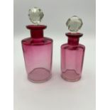 Two vintage pink scent bottles having clear faceted cut glass globe stoppers.