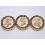 A set of three plaster wall plaques with images of cupid, oval shaped, 10cms long, 8cms wide