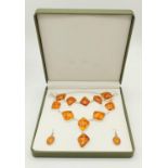 A modern silver and amber necklace, bracelet and earrings set, in a presentation box.