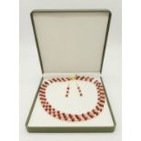 A three row of pink pearls and rubies necklace with matching earrings set. In a presentation case .