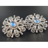 A pair of 18 K white gold earrings with a central oval moonstone surrounded by numerous brilliant