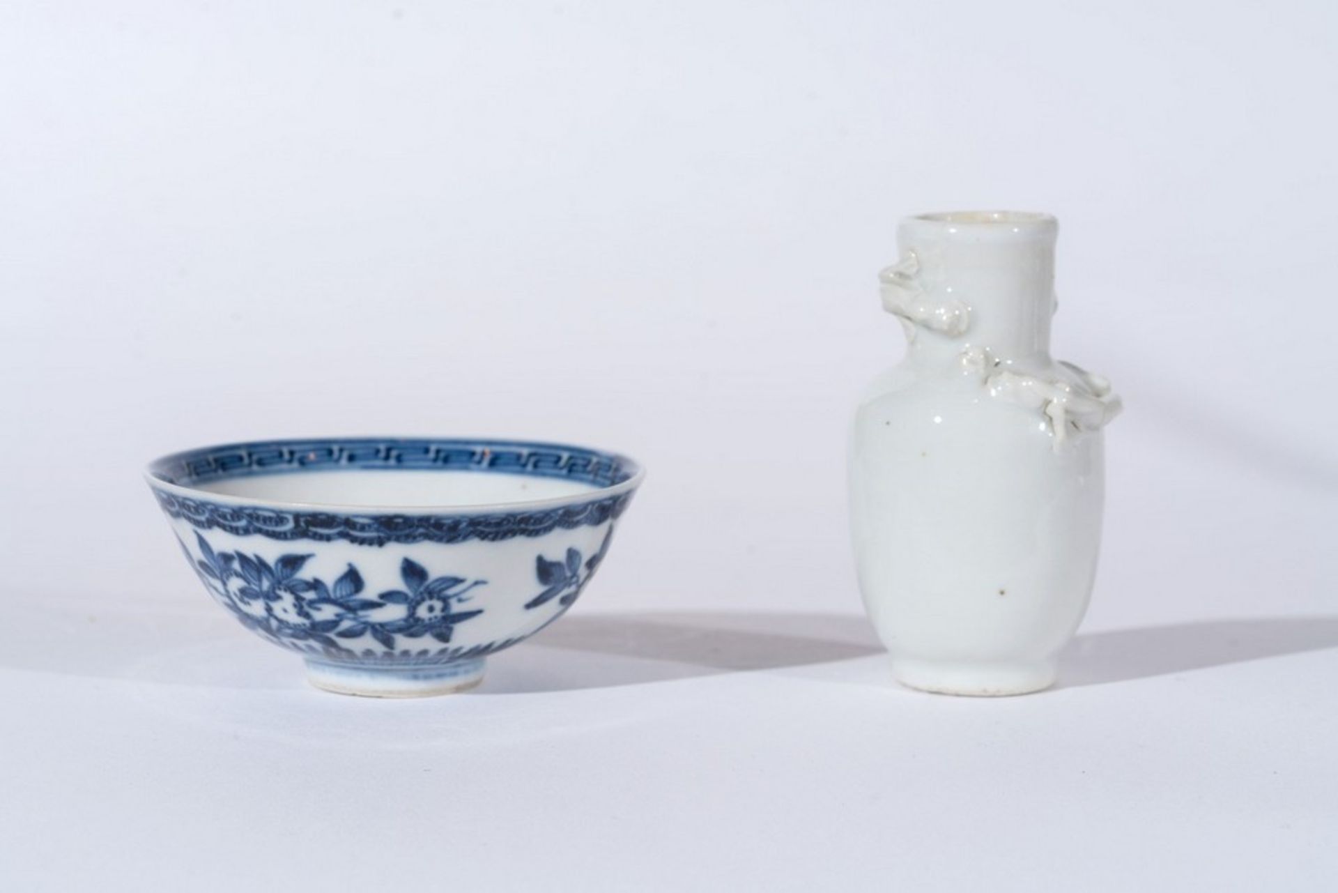 Arte Cinese A small white porcelain vase decorated with moulded chilong and small blue and white po