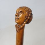 A 19th century folk art walking stick, the carved handle in the form of a lady in a bonnet and