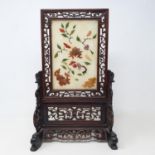 A Chinese table screen, with a pierced hardwood frame, the screen inset with hard stones in floral