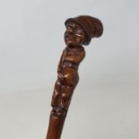 A 19th century folk art walking stick, the handle carved in the form of a poacher concealing his