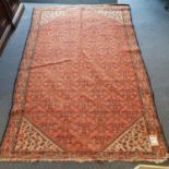 A Persian red ground rug, main green border, centre with repeating foliate forms, 198 x 130 cm