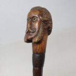 An early 20th century folk art cane, the handle carved in the form of a gentleman with a