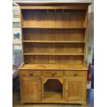 A stripped pine dresser, the three tier plate rack above a base with three drawers, a dog kennel and