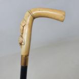 A walking stick, with carved ivory handle in the form of a hand grasping a rose, on ebonised