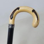 A walking stick, with carved ivory handle inlaid with horn snake, on ebonised shaft