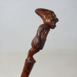 A 19th century folk art walking stick, the handle carved in the form of a jester, with glass eyes,