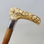 A walking stick, the ivory handle carved face masks, with silver collar, on hardwood shaft, 84 cm