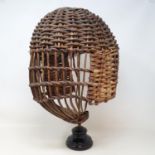 A miner's wicker safety helmet, and a brass stand, 43 cm high