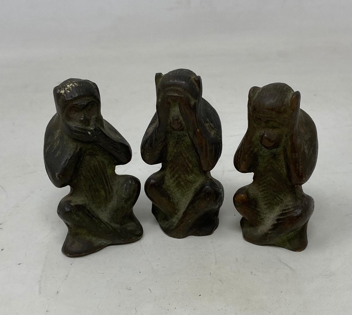 A set of three bronze monkeys, see no evil, hear no evil, speak no evil, on wooden stand, and
