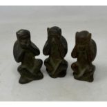 A set of three bronze monkeys, see no evil, hear no evil, speak no evil, on wooden stand, and