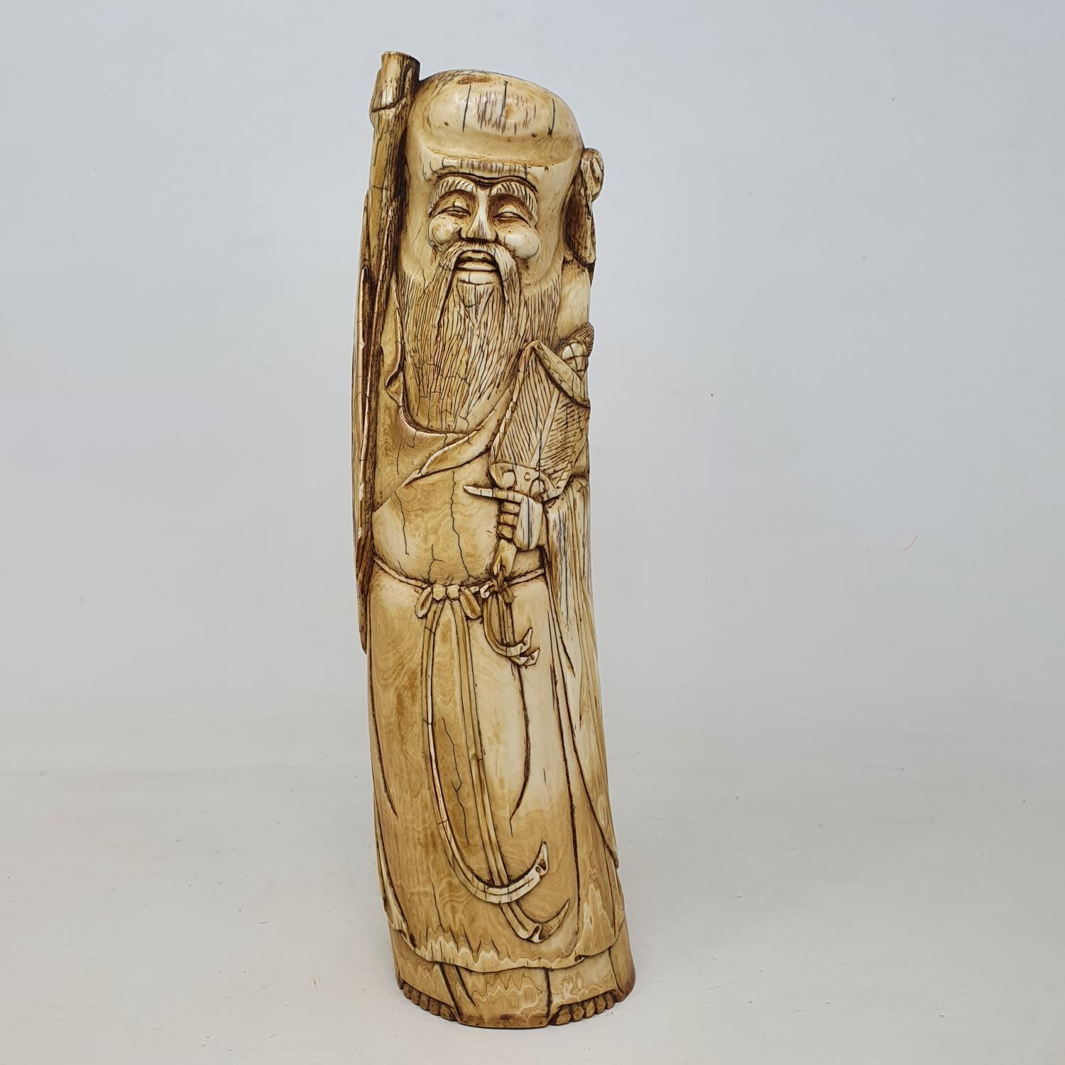 An early 20th century Chinese ivory tusk, carved in the form of Shou Lao, 28 cm high