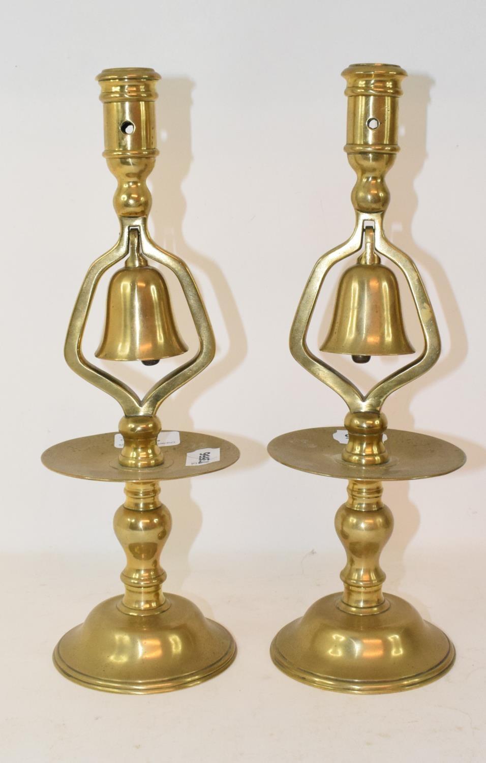 A pair of Victorian brass candlesticks, with bells, with broad drip pans and circular bases, 33 cm