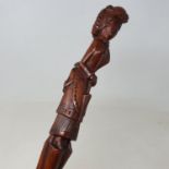 A 19th century folk art walking stick, the handle carved in the form of a Victorian lady carrying an